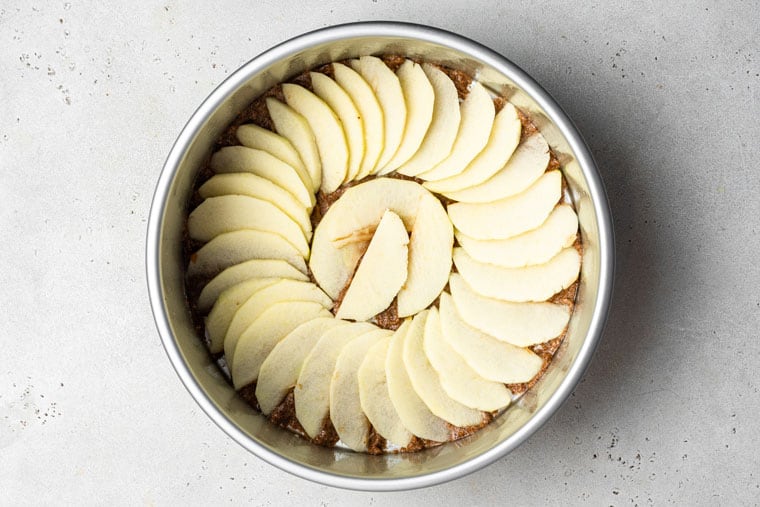 This apple upside-down cake is a show-stopping fall dessert with perfectly layered caramelized apple slices on a tender cinnamon-spiced cake. unbaked apple cake in a pan