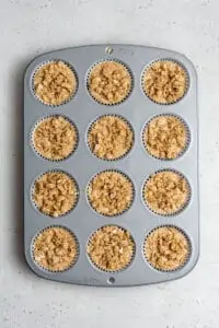 overhead of a muffin tin filled with apple muffin batter