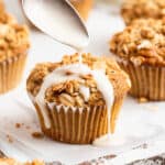 pouring white glaze over an apple cinnamon muffin