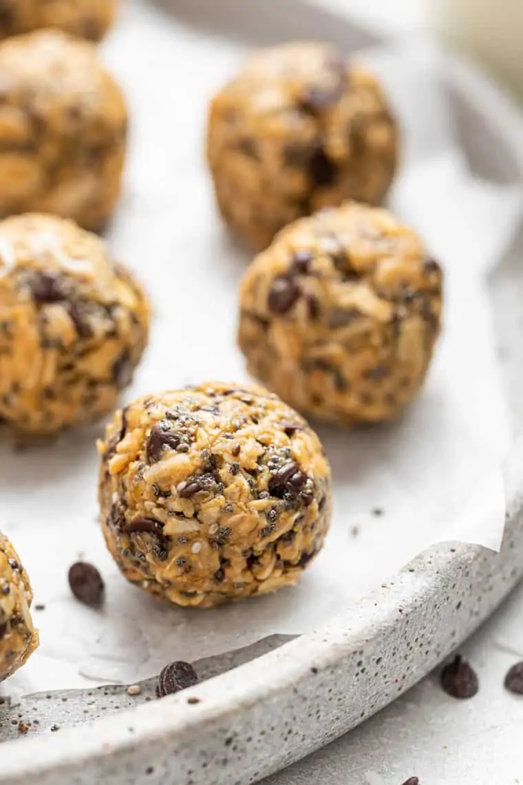 These peanut butter no-bake energy bites are made with oatmeal, coconut, chia and flax so they're super healthy, but they taste like a treat! close up on a peanut butter energy bite on paper