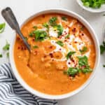 bowl of red lentil soup with cream and herbs