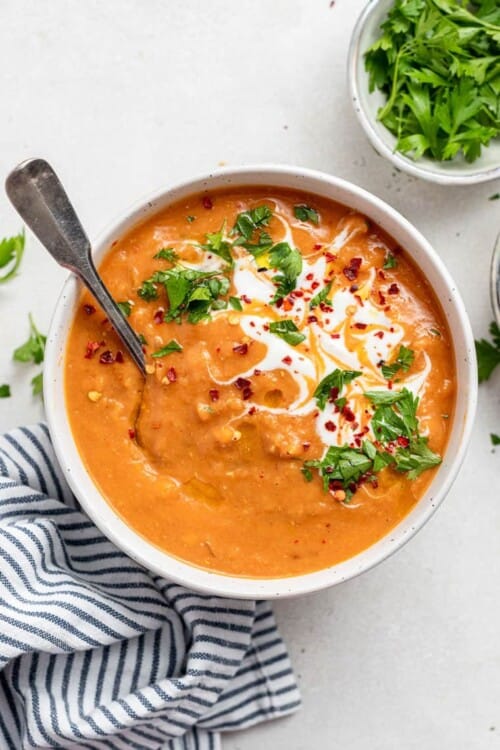 bowl of red lentil soup with cream and herbs
