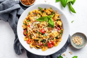 white bowl of bowtie pasta with sun dried tomato pesto