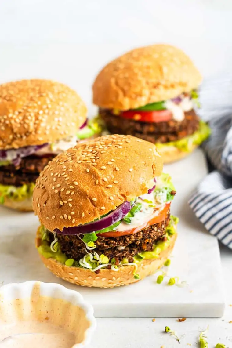 three veggie burgers on sesame seed buns with red onion and tomato