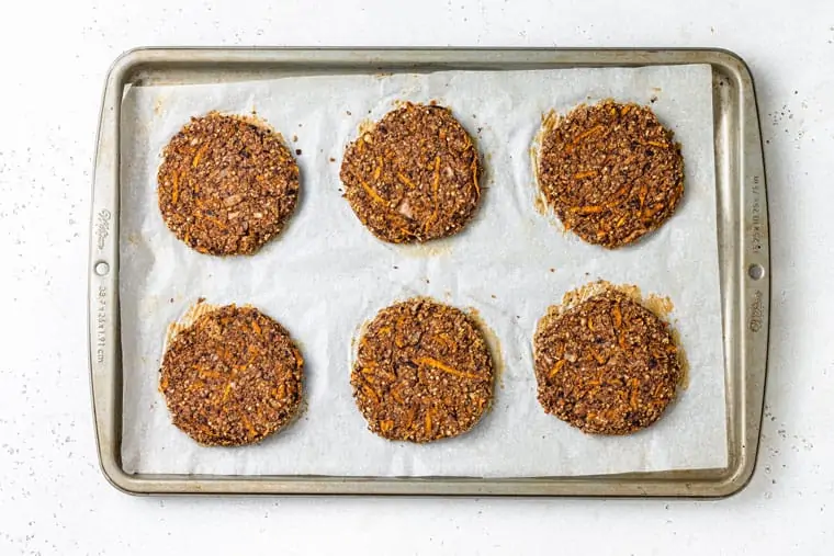 six baked black bean burgers on a baking sheet