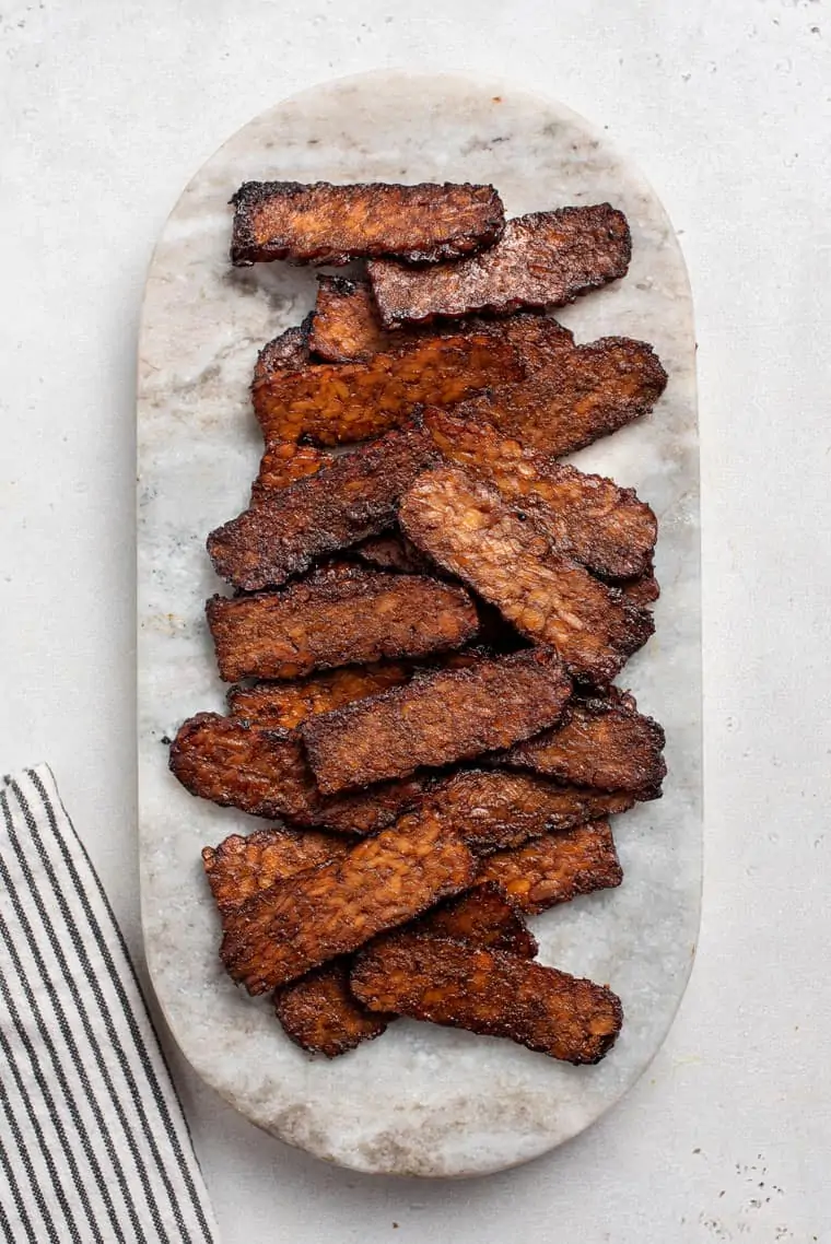 overhead of cooked tempeh bacon on marble board