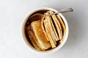 overhead of thinly sliced tempeh marinating in sauce to make tempeh bacon