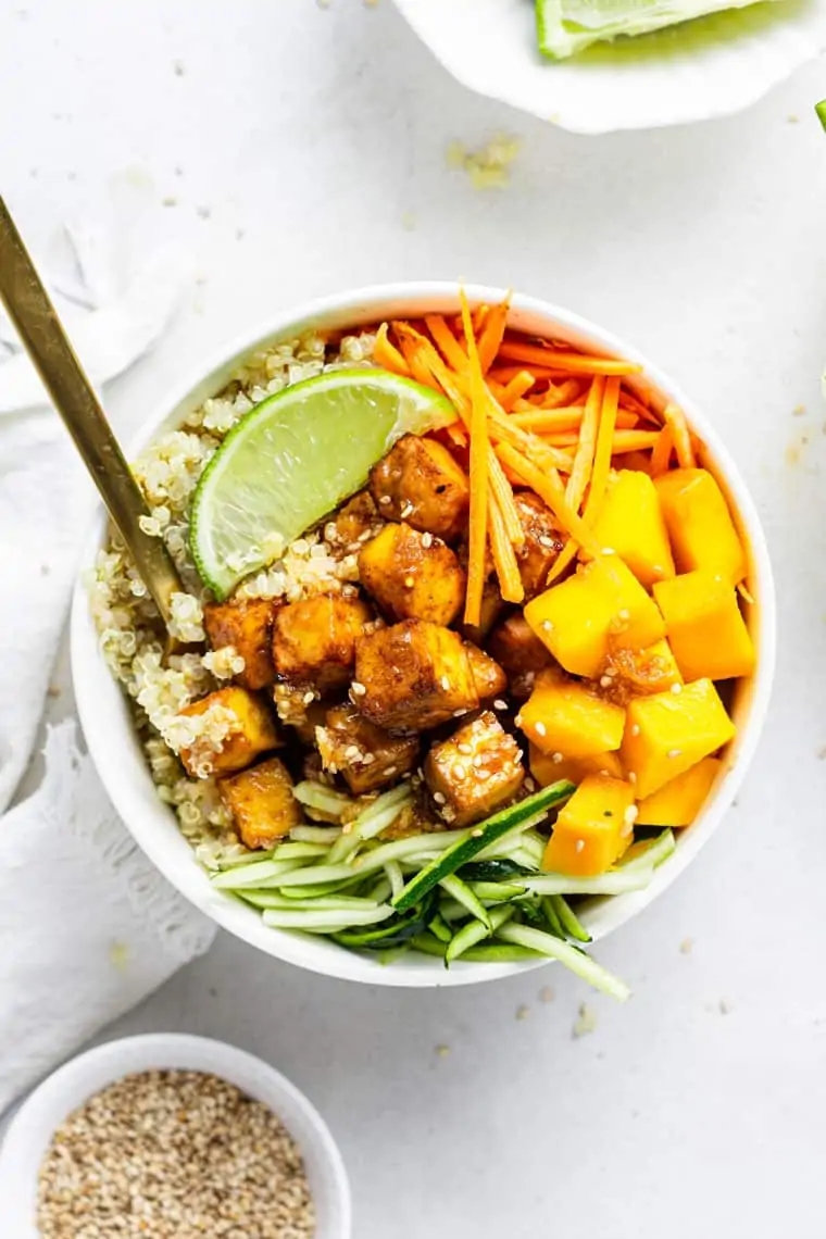 white bowl of teriyaki tofu, quinoa and mango