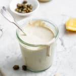 overhead of a glass jar with vegan caesar dressing with capers