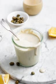 overhead of a glass jar with vegan caesar dressing with capers