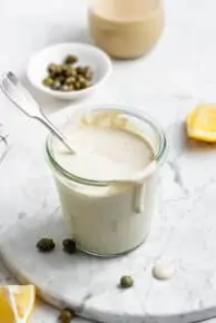 overhead of a glass jar with vegan caesar dressing with capers