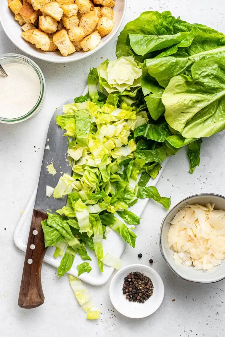 chopping romaine lettuce on a cutting board for salad