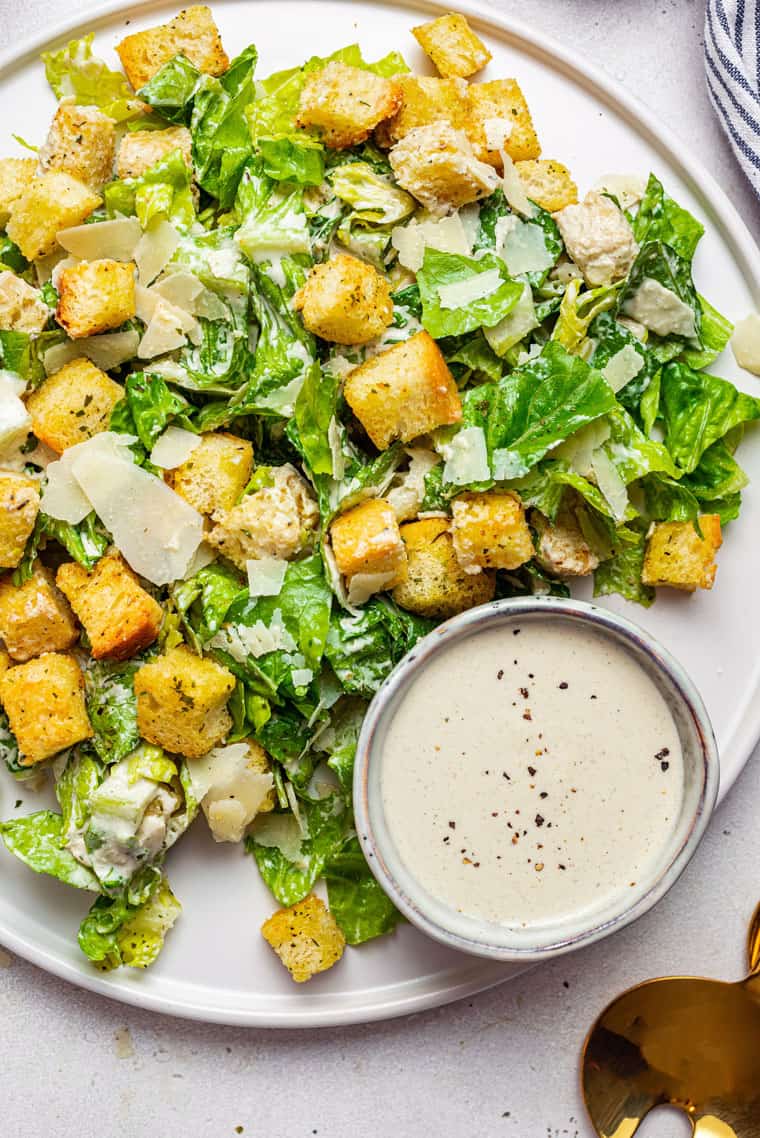 white plate with vegan caesar salad and dressing