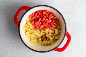 overhead of red pot with tomatoes and smoked paprika for vegan corn chowder