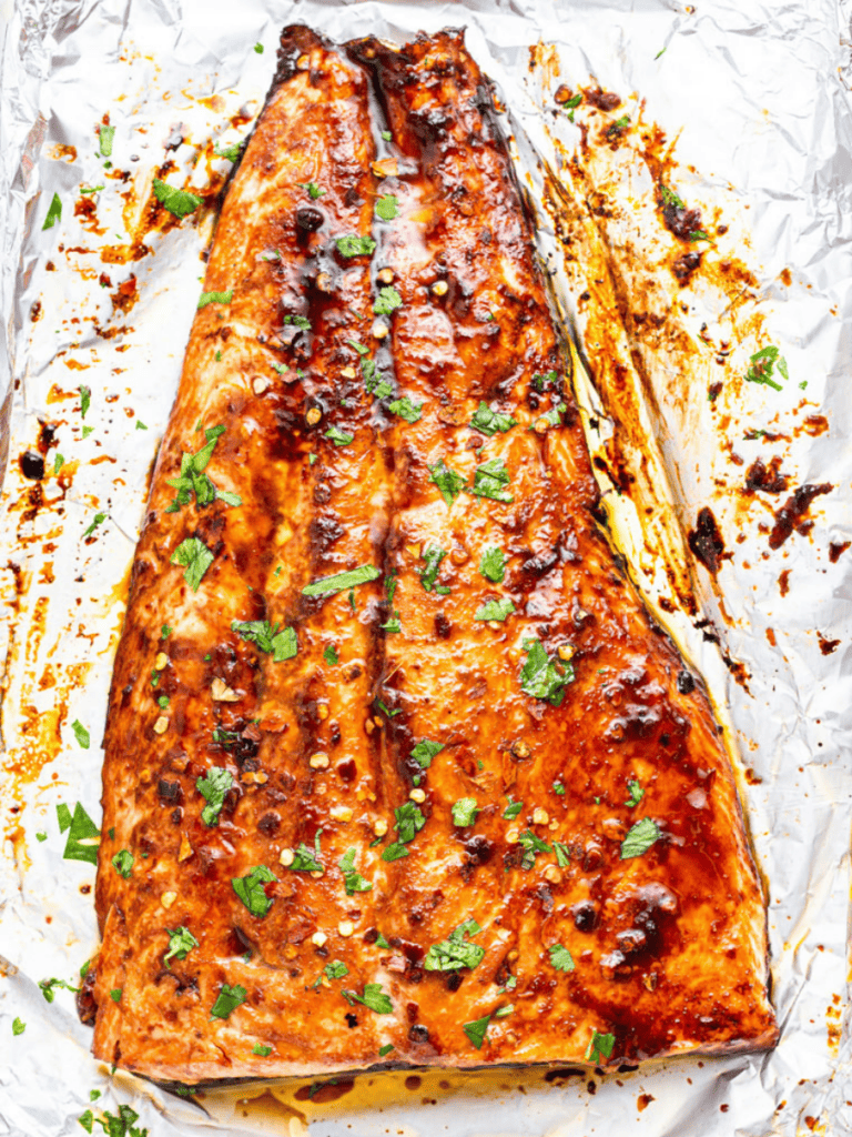 Overhead view of baked firecracker salmon on foil-lined pan