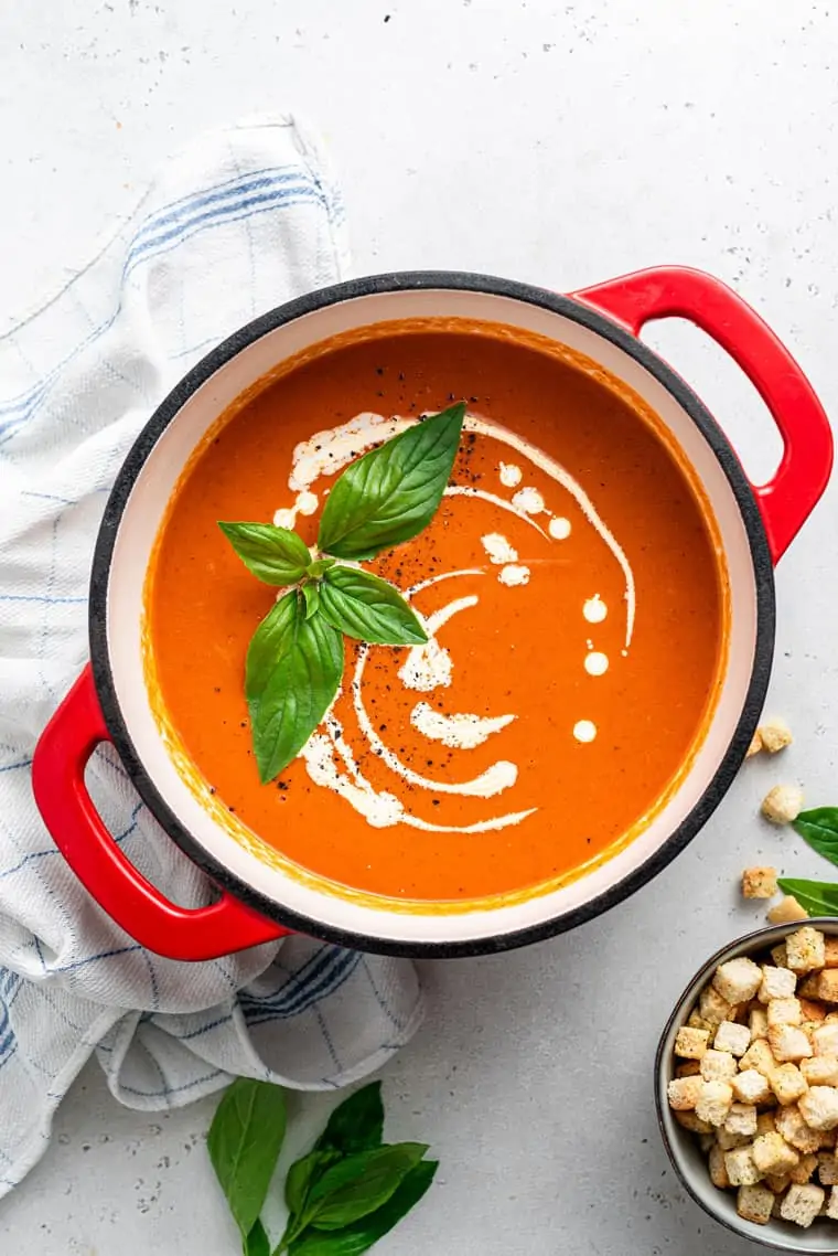 pot of tomato soup with cream and basil