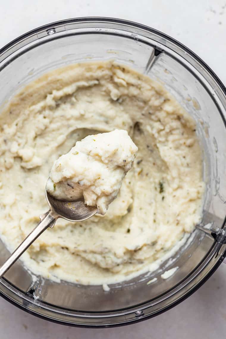 food processor with mashed cauliflower on a spoon