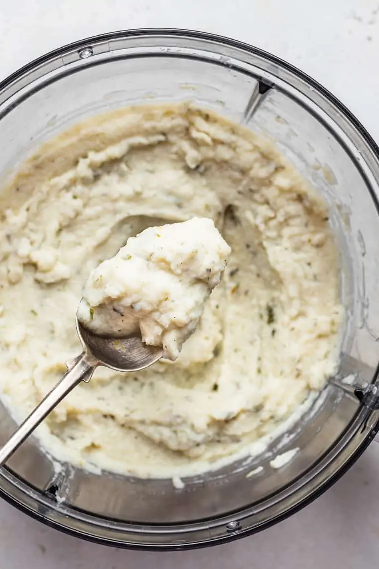 food processor with mashed cauliflower on a spoon