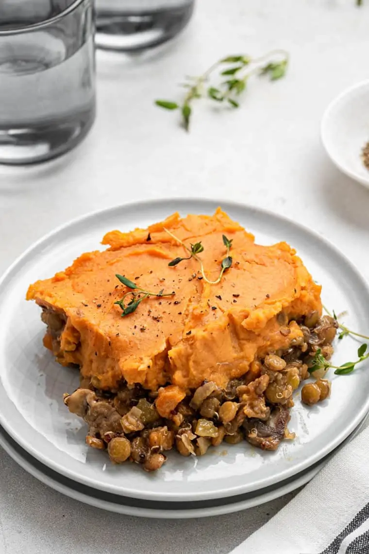This vegan shepherd's pie is a hearty comfort meal perfect for the holidays, with a lentil-quinoa filling and whipped sweet potato topping. slice of shepherd's pie with sweet potato crust and lentils