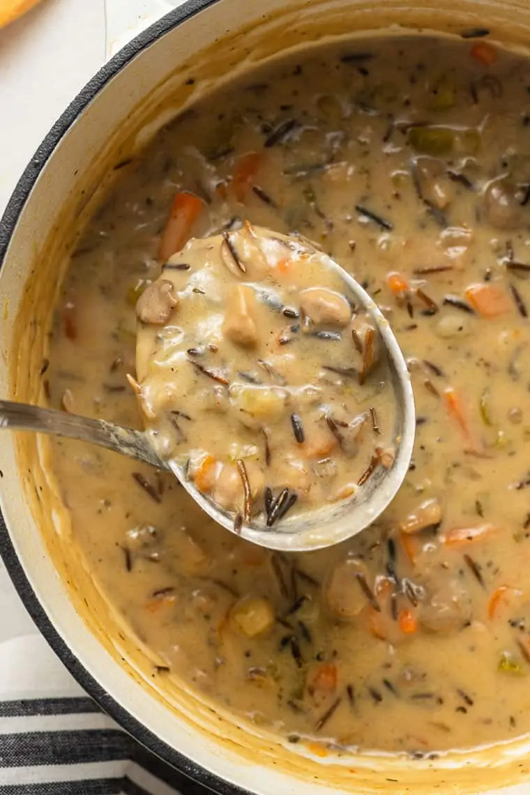 Close up of a ladle scooping a spoonful of soup out of a pot of wild rice soup