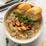 bowl of creamy wild rice soup with thyme and bread