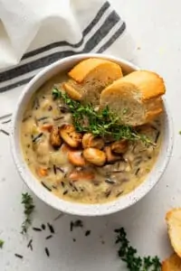 bowl of creamy wild rice soup with thyme and bread