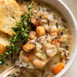 spoon of creamy wild rice soup with thyme and bread