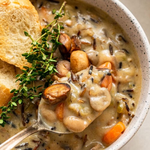 spoon of creamy wild rice soup with thyme and bread