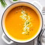 Pot of sweet potato ginger soup with cream and chives.