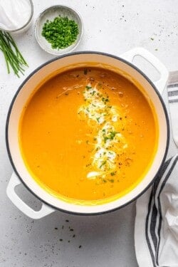 Pot of sweet potato ginger soup with cream and chives.