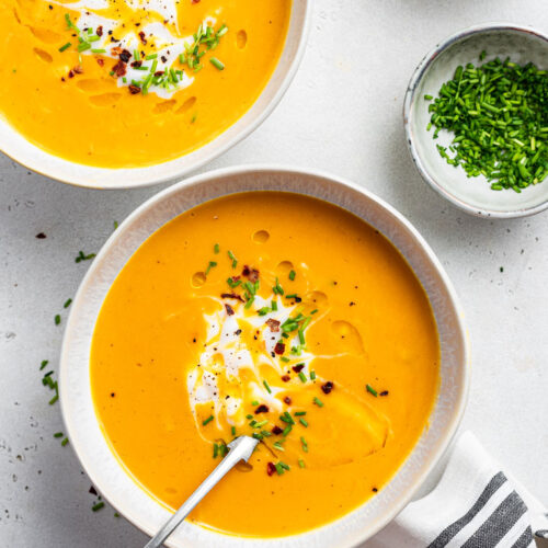 two bowls of sweet potato soup with chives