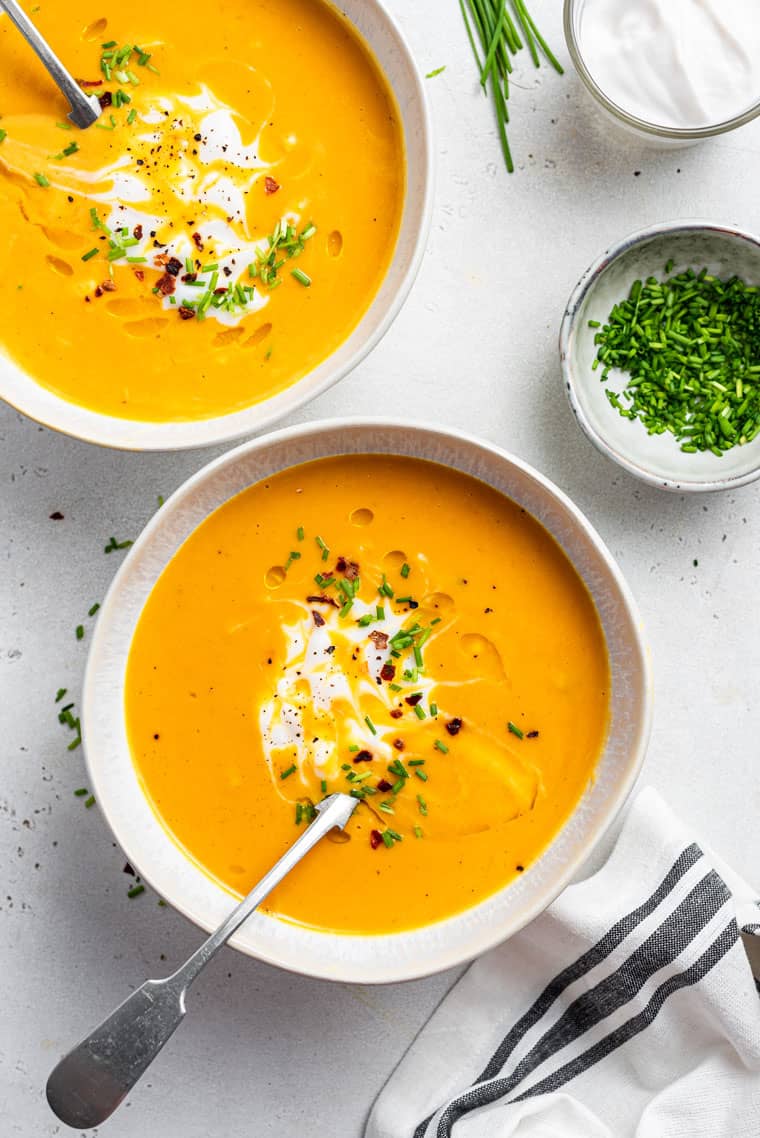 two bowls of sweet potato soup with chives