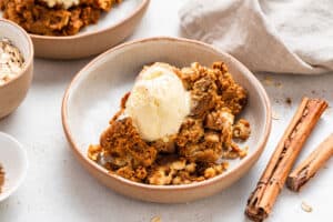 Pumpkin crisp in a bowl topped with vanilla ice cream.