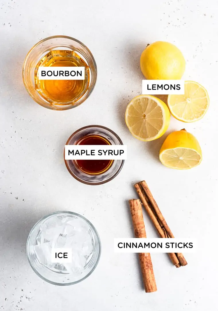 ingredients for drink with bourbon, maple syrup, lemon and cinnamon