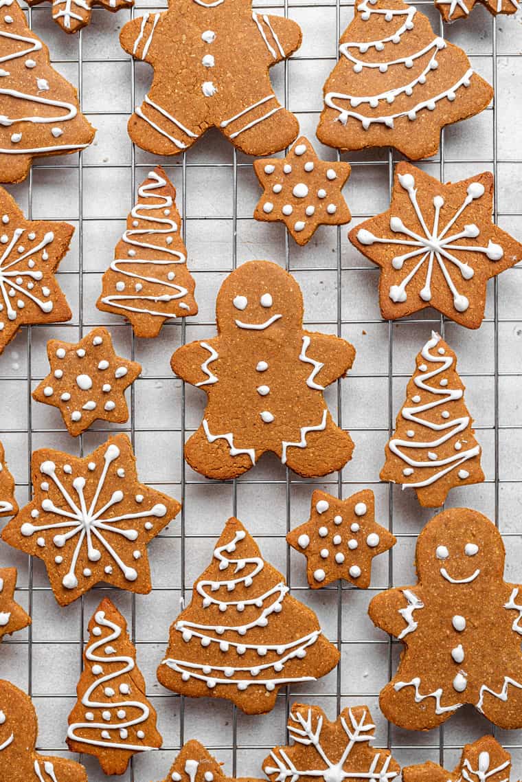 How to make vegan gingerbread cookies for the holidays! Bonus: they’re also gluten-free, which means you’ll have a treat everyone can enjoy. decorated vegan gingerbread cookies on a wire rack