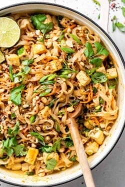 skillet with tofu pad thai and limes