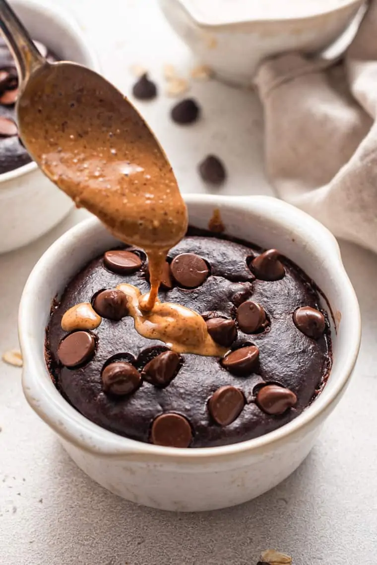 pouring almond butter on dark chocolate baked oatmeal