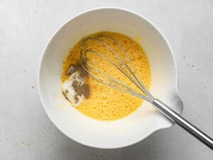 whisking eggs and seasonings in a bowl
