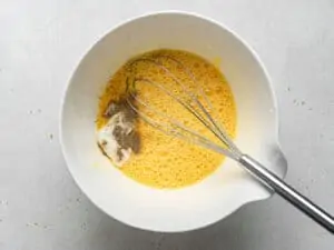 whisking eggs and seasonings in a bowl