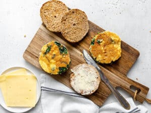 assembling breakfast sandwiches with eggs, kale and english muffins