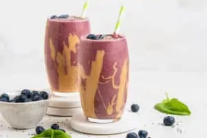 two glasses of blueberry peanut butter smoothie
