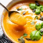 bowl of roasted butternut squash soup with a spoon eating the soup