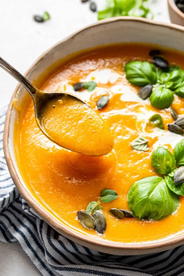 bowl of roasted butternut squash soup with a spoon eating the soup