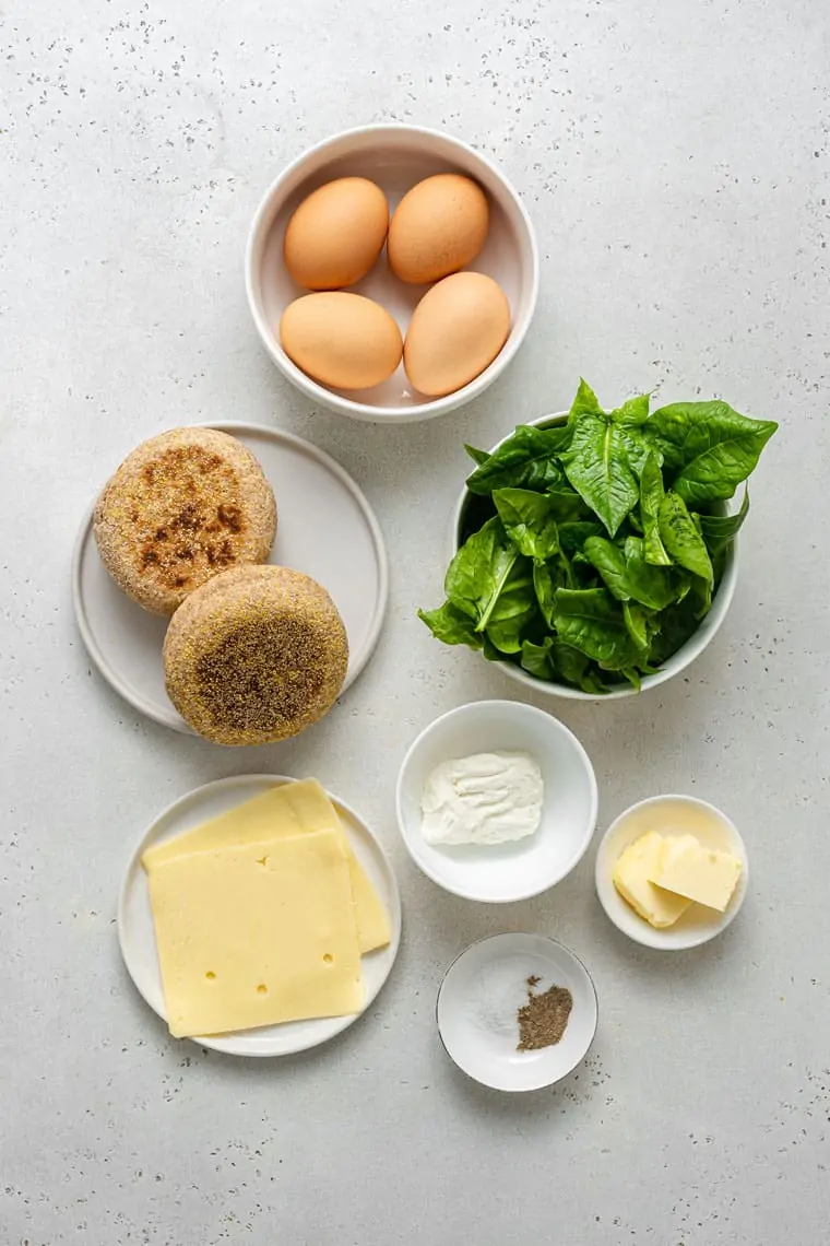ingredients for breakfast sandwiches with eggs, spinach, muffins, cheese and butter