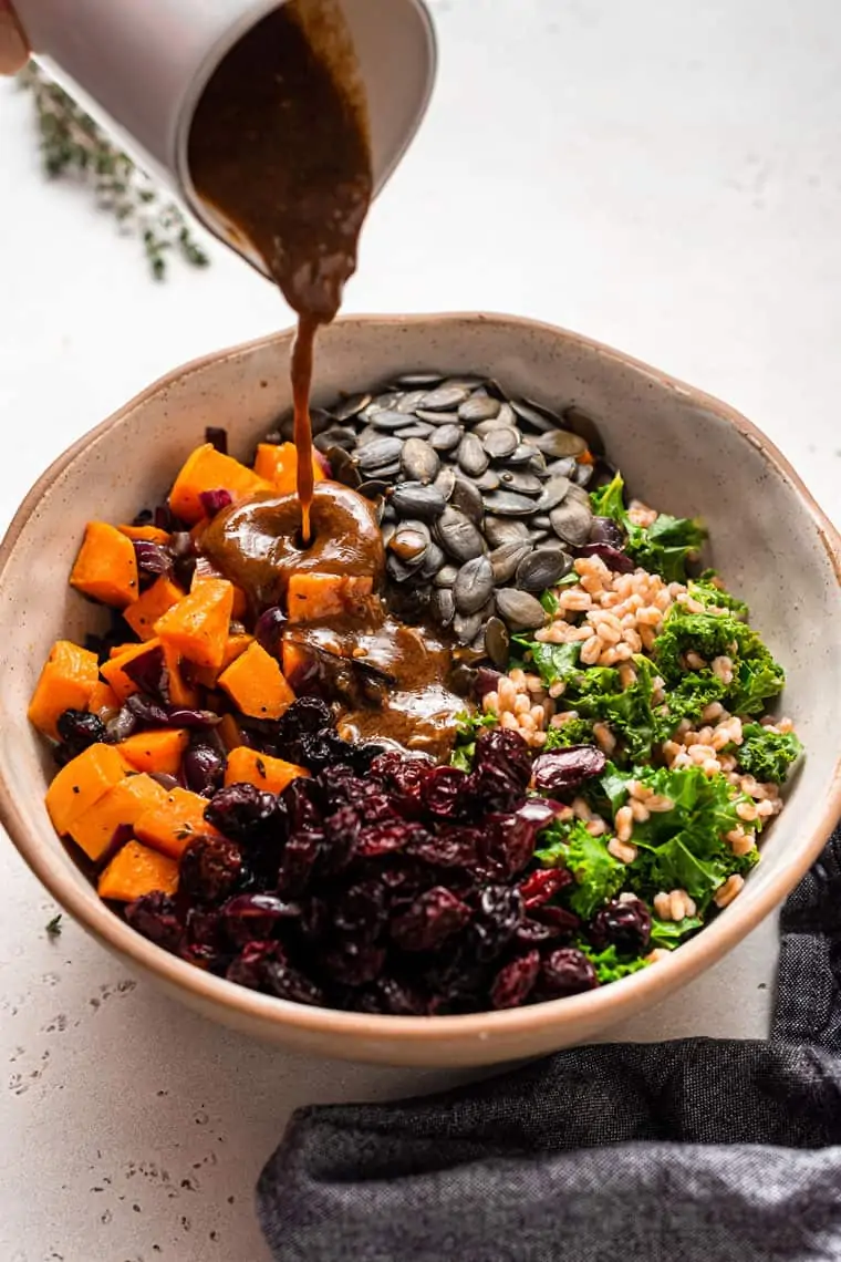 pouring balsamic dressing over farro salad
