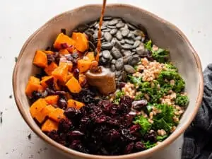 Dressing drizzled over a bowl of farro salad ingredients.