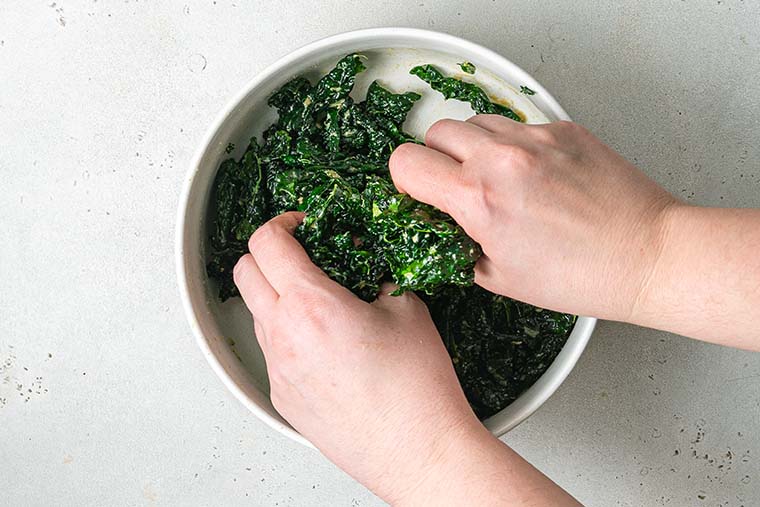 hands massaging chopped kale leaves