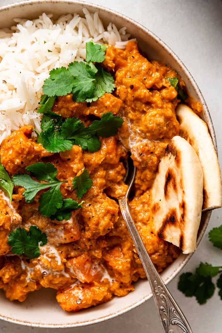 This creamy red lentil curry with sweet potatoes is a one-pot recipe that delivers lots of cozy comfort. It's an easy, filling vegan dinner! close up on sweet potato lentil curry with rice