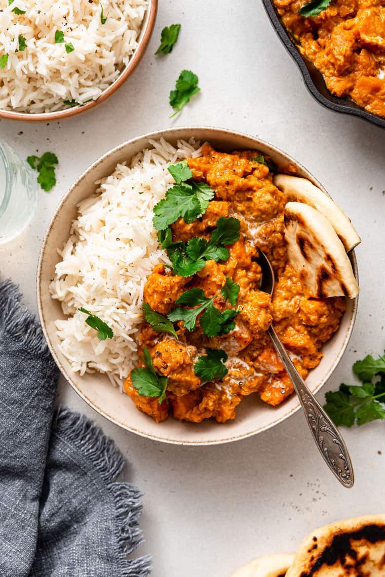 This creamy red lentil curry with sweet potatoes is a one-pot recipe that delivers lots of cozy comfort. It's an easy, filling vegan dinner! bowl of sweet potato and red lentil curry with rice and naan