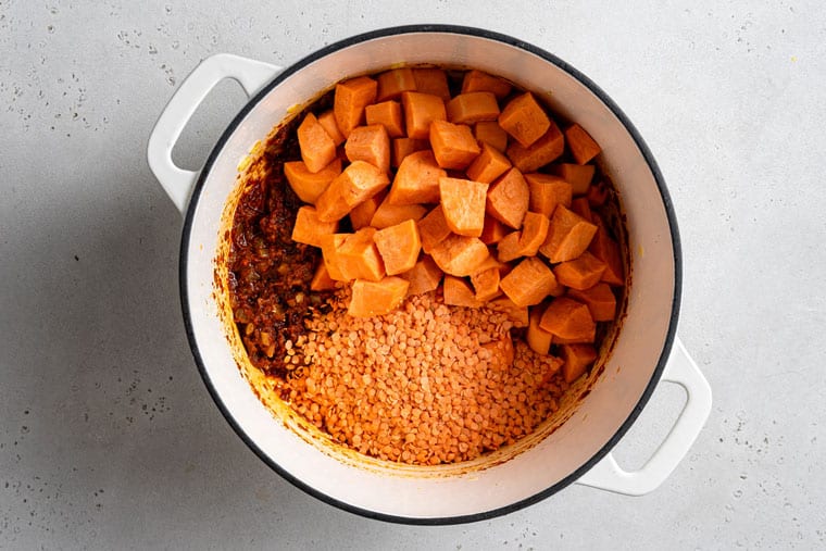 This creamy red lentil curry with sweet potatoes is a one-pot recipe that delivers lots of cozy comfort. It's an easy, filling vegan dinner! sweet potato and lentils in a pot with curry paste